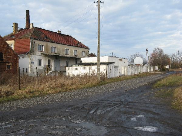 Plac postacyjny. Z lewej mleczarnia i ogrodzenie (za nim miaa byc bocznica). Wg mapy tor by w miejscu bruku, co jest dziwne - bruk zdaje si byc wsplczesny budowie kolei. Widok z szosy, w kierunku Stypuowa (oczyszczalni). I. 2008, fot. M. Bonisawski